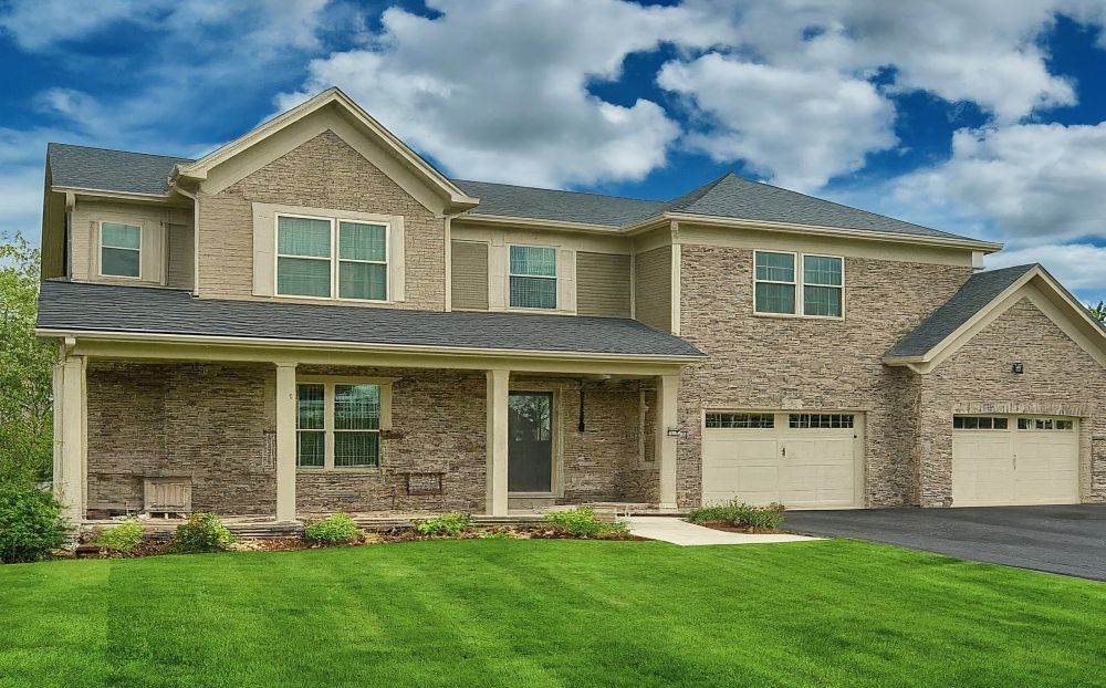 Stittsville Neighbourhoods. A two-story house in Stittsville, surrounded by a neatly manicured lawn and trees.